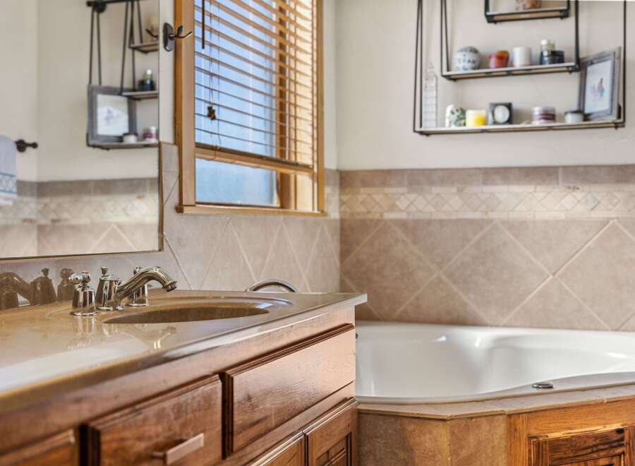 This stunning bathroom features a luxurious soaking tub and a stylish vanity with a sleek faucet.