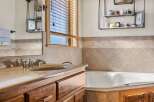 This stunning bathroom features a luxurious soaking tub and a stylish vanity with a sleek faucet.