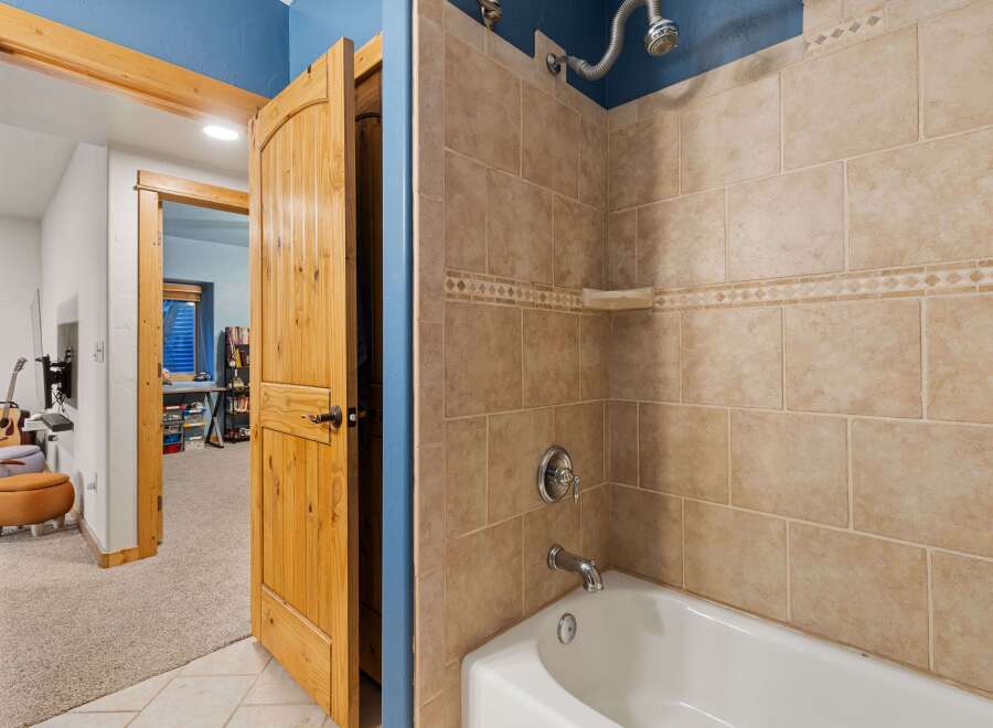 Step into this inviting bathroom, featuring a stylish combination of warm-toned tiles and a pristine white bathtub.