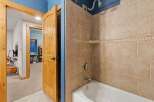 Step into this inviting bathroom, featuring a stylish combination of warm-toned tiles and a pristine white bathtub.