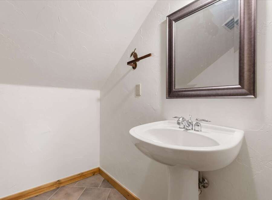 Discover the charm of this unique bathroom! Featuring a stylish pedestal sink and a decorative mirror, this space offers both functionality and aesthetic appeal.
