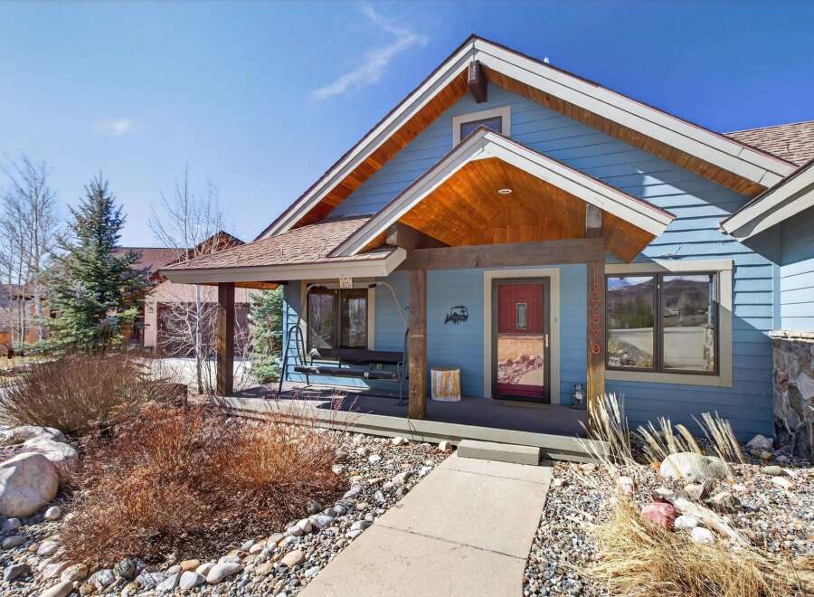 Charming blue house with a welcoming porch and a touch of rustic elegance.