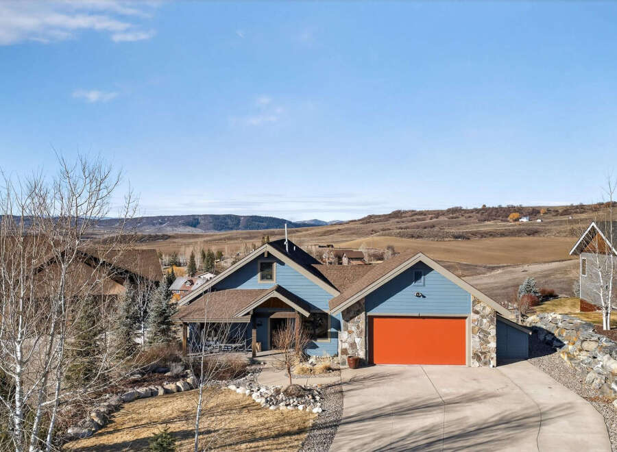 This stunning property boasts a beautiful exterior with a vibrant orange garage door, complemented by a stone facade.