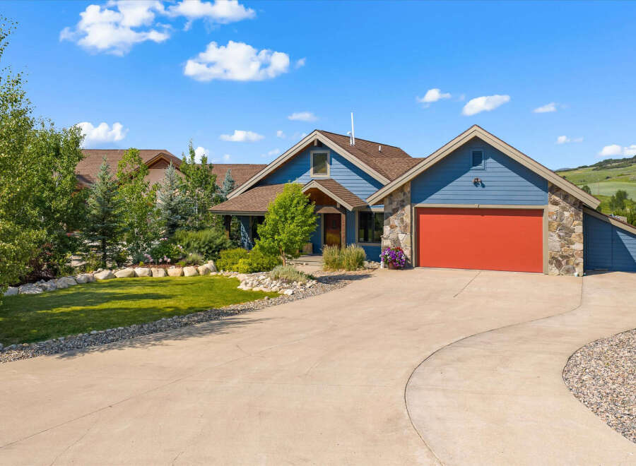 Discover this stunning blue home featuring a vibrant red garage door and charming stone accents.