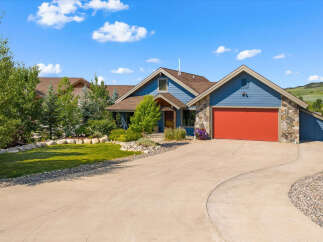 Discover this stunning blue home featuring a vibrant red garage door and charming stone accents.