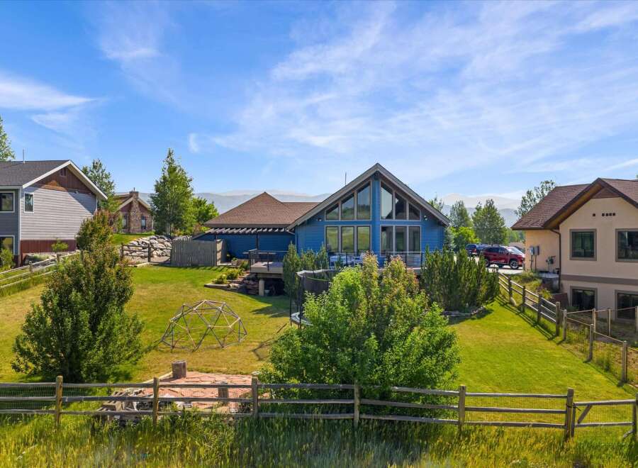 Discover this stunning property featuring a vibrant blue home with expansive windows and a spacious deck, perfect for enjoying the scenic mountain views.