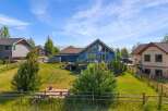 Discover this stunning property featuring a vibrant blue home with expansive windows and a spacious deck, perfect for enjoying the scenic mountain views.