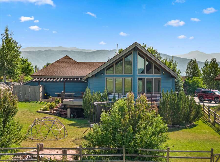 Experience breathtaking mountain views from this stunning blue home, featuring a spacious deck perfect for entertaining and large windows that flood the interior with natural light.