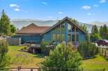 Experience breathtaking mountain views from this stunning blue home, featuring a spacious deck perfect for entertaining and large windows that flood the interior with natural light.