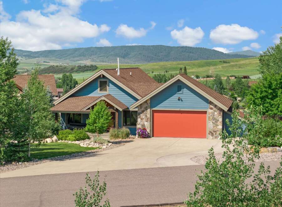 Discover this charming blue home nestled against a backdrop of rolling green hills and majestic mountains.