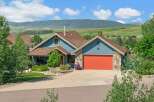 Discover this charming blue home nestled against a backdrop of rolling green hills and majestic mountains.