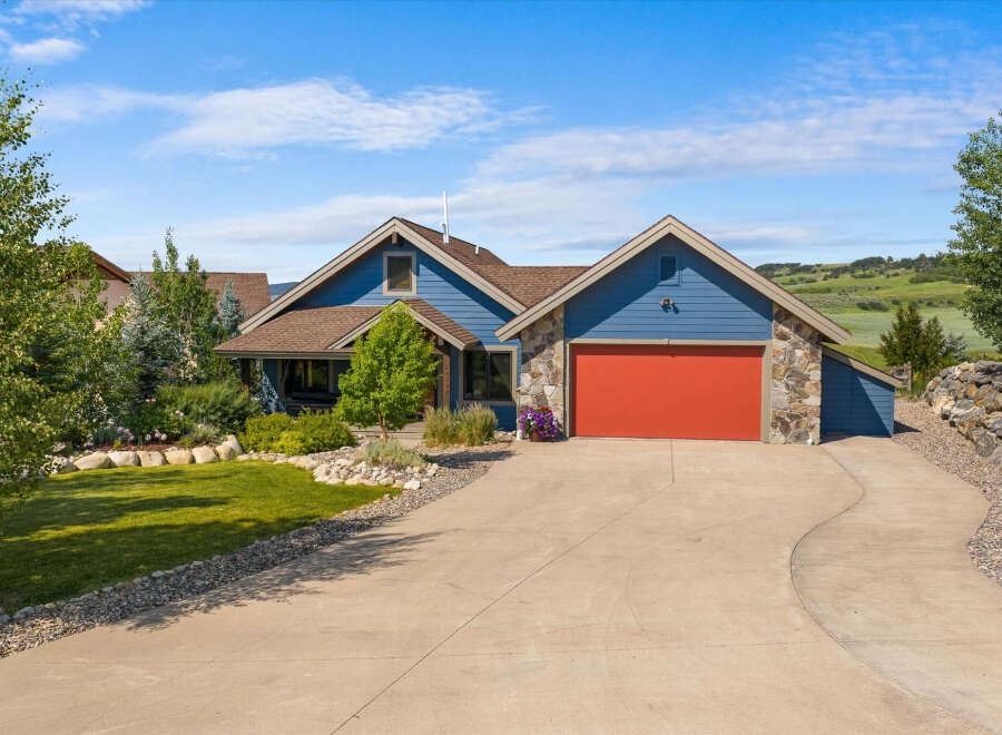 Discover this charming blue home featuring a vibrant red garage door and natural stone accents.
