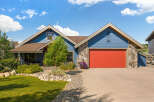 Charming blue siding home featuring a vibrant red garage door and natural stone accents.