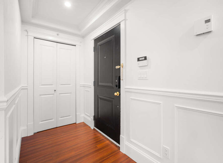 Step into this inviting entryway, featuring a striking black door and elegant white wainscoting.