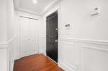 Step into this inviting entryway, featuring a striking black door and elegant white wainscoting.