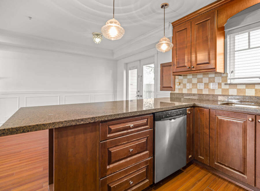 This stunning kitchen boasts rich, wooden cabinetry and a spacious granite countertop, perfect for meal preparation and entertaining.