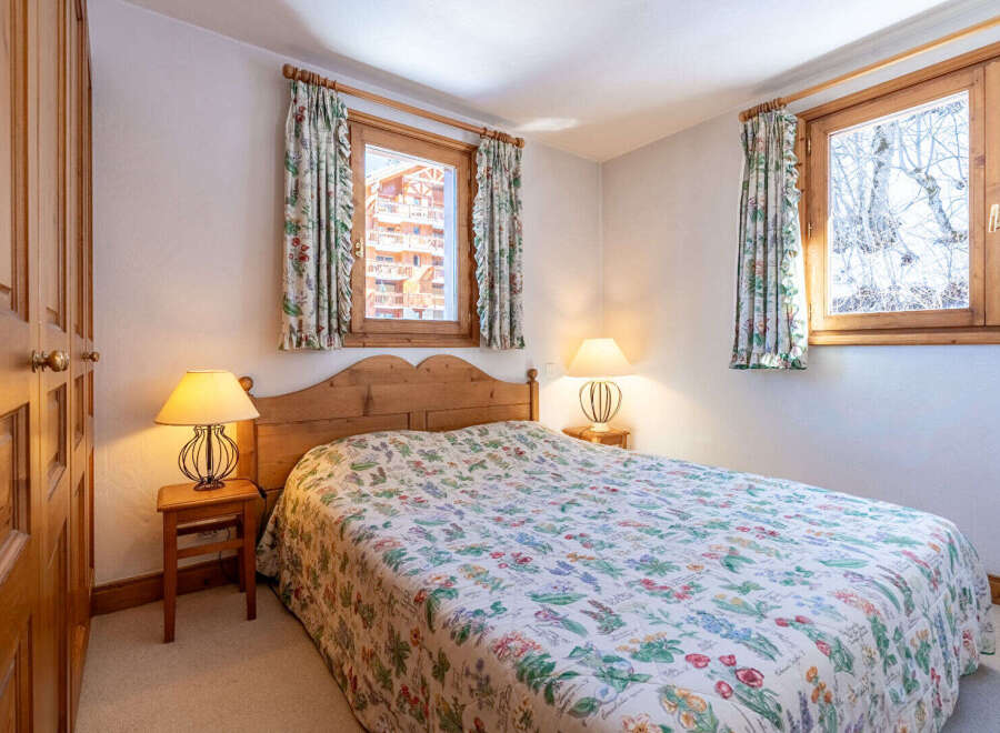 This charming bedroom features a cozy double bed adorned with a floral patterned quilt, creating a warm and inviting atmosphere.