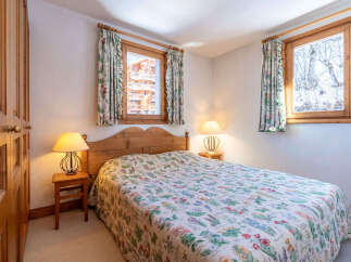 This charming bedroom features a cozy double bed adorned with a floral patterned quilt, creating a warm and inviting atmosphere.