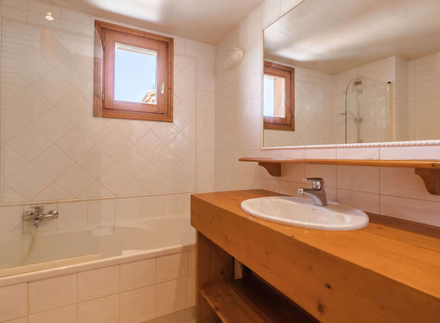 This charming bathroom features a classic design with a wooden vanity and a bright, airy feel.