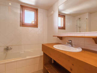 This charming bathroom features a classic design with a wooden vanity and a bright, airy feel.