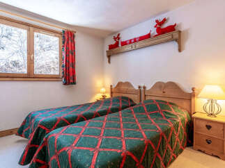 This cozy bedroom features two twin beds with a charming quilt design, perfect for a comfortable stay.