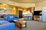 This stunning property boasts a spacious living area with a comfortable blue sofa, perfect for relaxing.