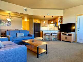 This stunning property boasts a spacious living area with a comfortable blue sofa, perfect for relaxing.