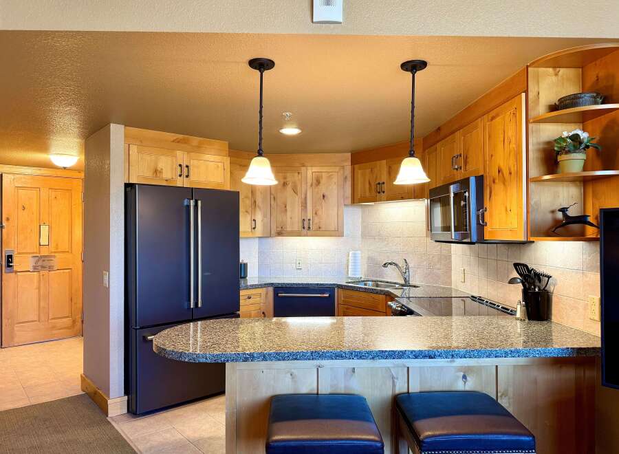 This stunning kitchen boasts beautiful wooden cabinetry, a sleek black refrigerator, and a stylish granite countertop.