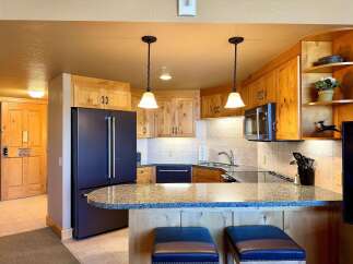This stunning kitchen boasts beautiful wooden cabinetry, a sleek black refrigerator, and a stylish granite countertop.