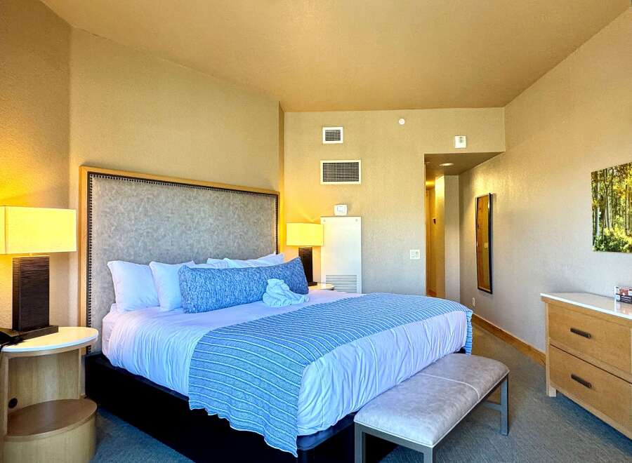 This luxurious bedroom features a king-sized bed with plush bedding and a stylish blue and white striped bed runner.
