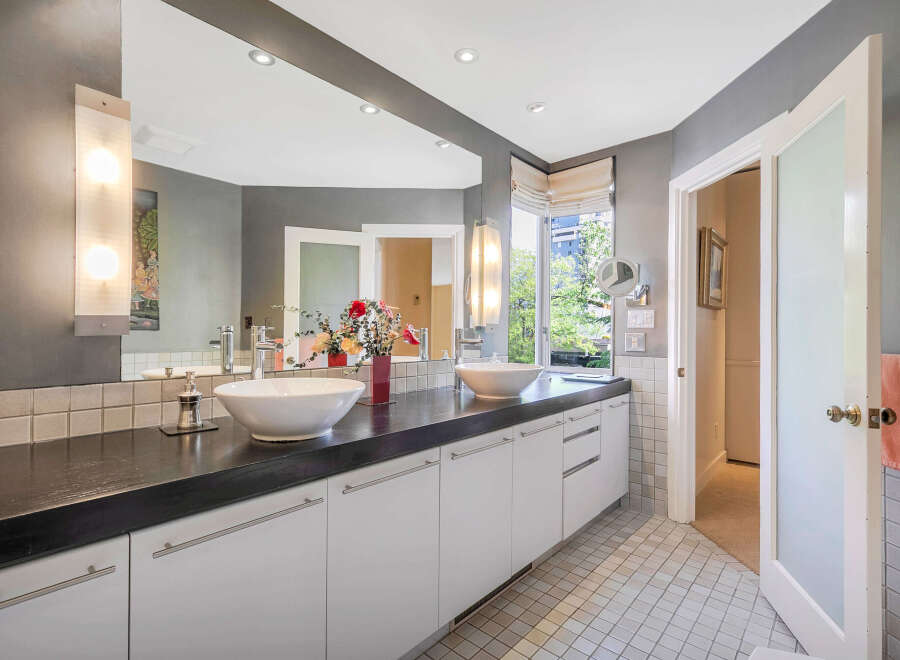 Step into luxury with this stunning bathroom, featuring a sleek black countertop and modern white cabinetry.