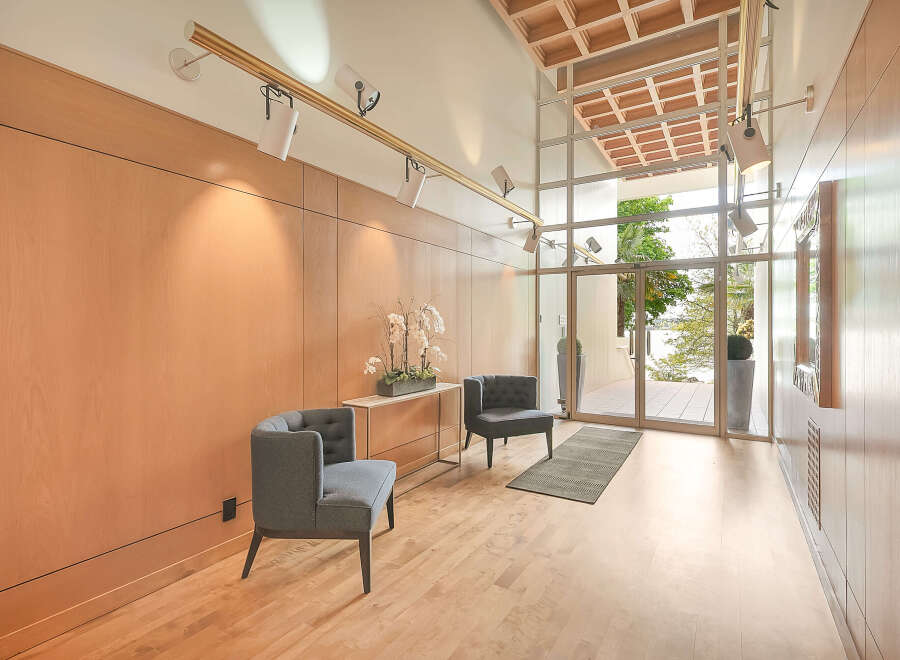 Step into luxury with this stunning entryway, featuring sleek wooden paneling and modern track lighting.
