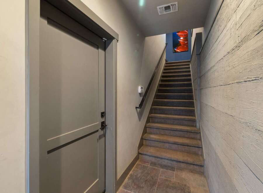 Step into this inviting entryway featuring a stylish staircase and a modern door.
