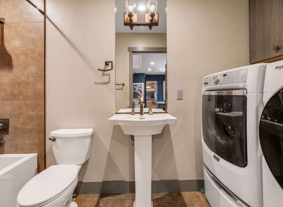 Step into this beautifully designed bathroom, featuring a modern pedestal sink and a convenient in-unit washer and dryer.
