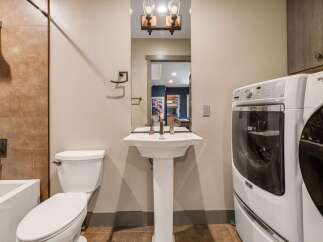 Step into this beautifully designed bathroom, featuring a modern pedestal sink and a convenient in-unit washer and dryer.