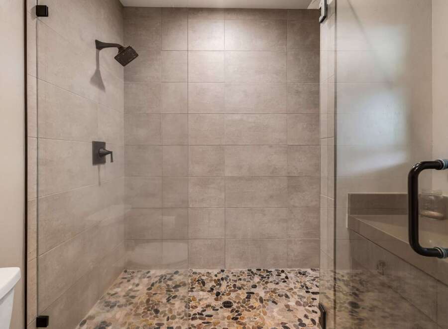 Step into luxury with this stunning shower featuring a pebble stone floor and sleek glass enclosure.