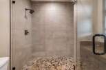 Step into luxury with this stunning shower featuring a pebble stone floor and sleek glass enclosure.