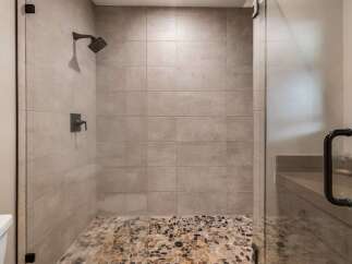 Step into luxury with this stunning shower featuring a pebble stone floor and sleek glass enclosure.