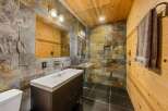 Step into luxury with this stunning bathroom featuring a unique stone tile shower and a sleek, modern vanity.