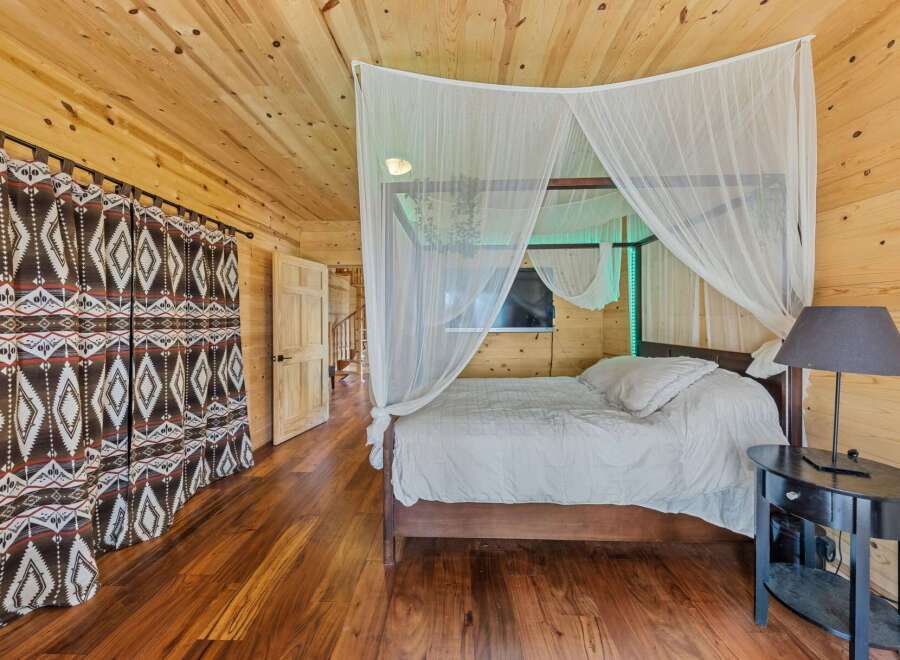 Step into this cozy bedroom featuring a unique wooden interior and a stylish canopy bed.