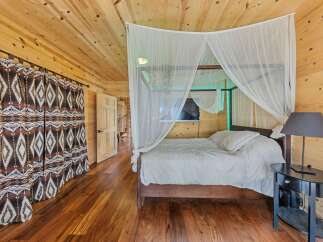 Step into this cozy bedroom featuring a unique wooden interior and a stylish canopy bed.