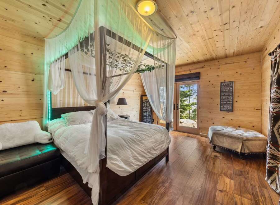 Step into a cozy bedroom retreat featuring a luxurious canopy bed draped with elegant white curtains.