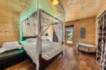 Step into a cozy bedroom retreat featuring a luxurious canopy bed draped with elegant white curtains.