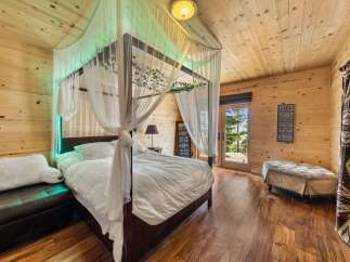 Step into a cozy bedroom retreat featuring a luxurious canopy bed draped with elegant white curtains.