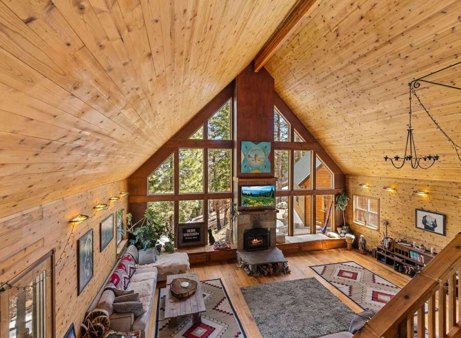 Step into a cozy mountain retreat with this stunning property, featuring a warm, inviting interior with exposed wooden beams and walls.