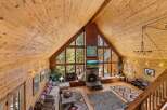 Step into a cozy mountain retreat with this stunning property, featuring a warm, inviting interior with exposed wooden beams and walls.