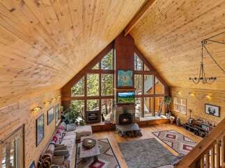 Step into a cozy mountain retreat with this stunning property, featuring a warm, inviting interior with exposed wooden beams and walls.