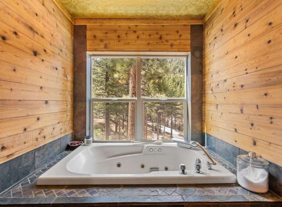 Indulge in the tranquility of this stunning bathroom, featuring a luxurious jacuzzi tub and breathtaking views of the surrounding forest.