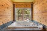 Indulge in the tranquility of this stunning bathroom, featuring a luxurious jacuzzi tub and breathtaking views of the surrounding forest.