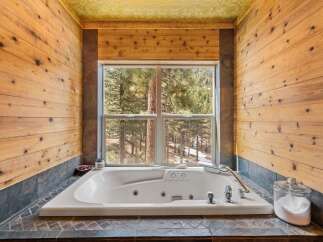 Indulge in the tranquility of this stunning bathroom, featuring a luxurious jacuzzi tub and breathtaking views of the surrounding forest.